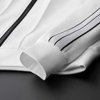 Close-up of the white track jacket showing the zip closure, ribbed cuff and twin-stripe sleeve detail
