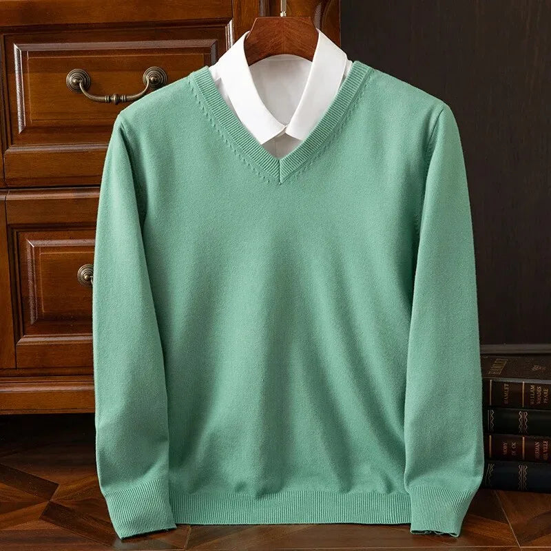 Sage green V-neck jumper with ribbed collar layered over a white shirt, displayed on a wooden hanger