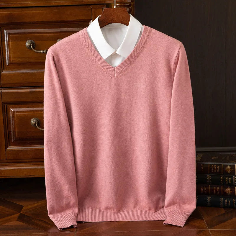Dusty pink V-neck jumper layered over a white shirt collar, styled on a hanger near stacked books
