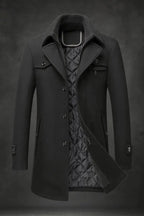 Black wool overcoat with double collar and quilted lining, front view showing flap pocket and buttoned cuffs