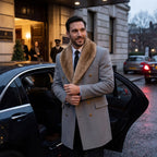 Man in grey double-breasted wool overcoat with brown faux fur shawl collar, stepping out of a car in the rain
