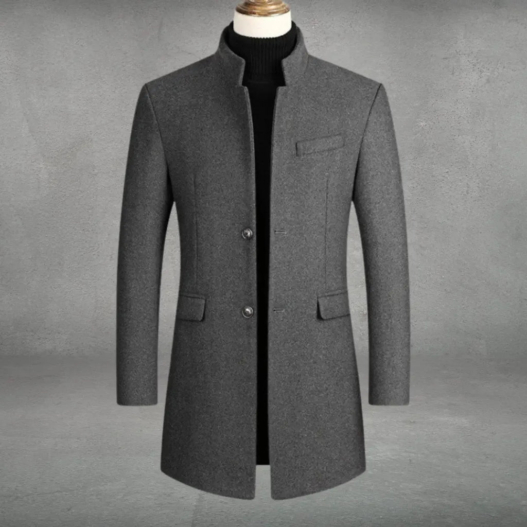 Grey wool-blend overcoat with stand collar, single-breasted button front and flap pockets, shown on mannequin with black polo neck jumper