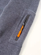 Close-up of front pocket with orange zip pull and ribbed cuff detail on grey hoodie