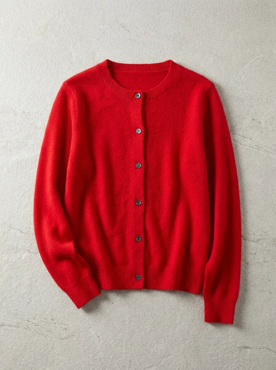 Red knitted cardigan with round neckline and dark tortoiseshell buttons, laid flat on a textured grey backdrop