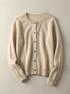 Beige cardigan in soft wool blend with crew neckline, shown flat against a light concrete background