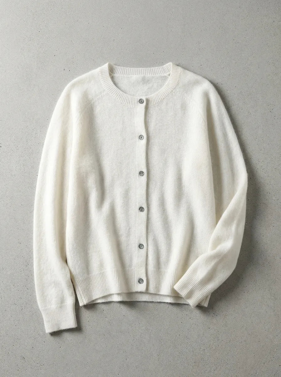 Ivory white cardigan with ribbed cuffs and button placket, laid flat on a neutral grey surface