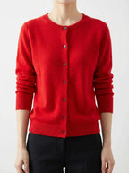 Close-up front view of a red crew-neck knitted cardigan with dark buttons, worn over a black top and trousers
