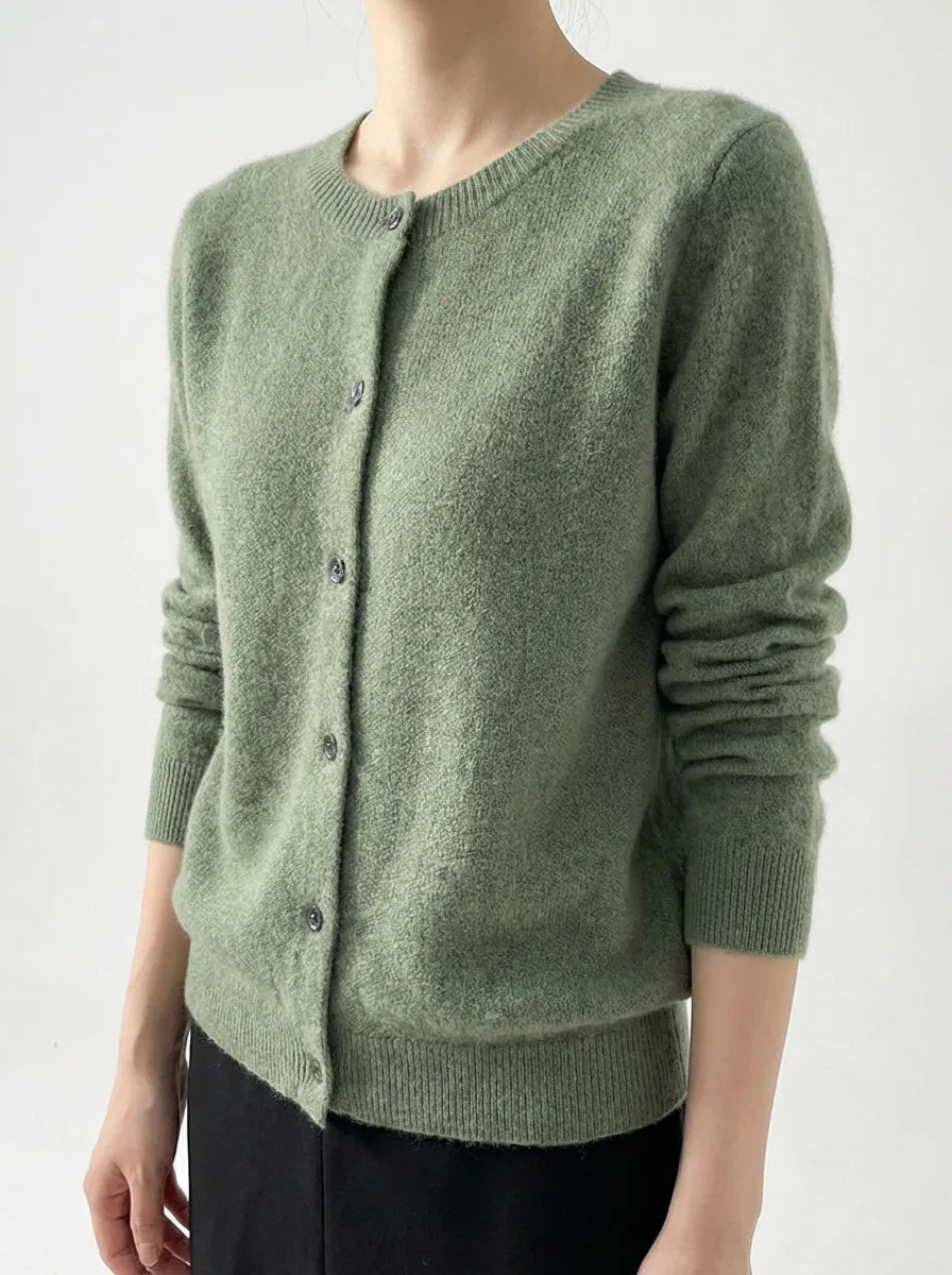 Angled view of a sage green knitted cardigan showing the ribbed cuffs and round neckline on a model