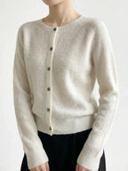 Front view of an ivory knitted cardigan with the top button undone, worn over a dark skirt