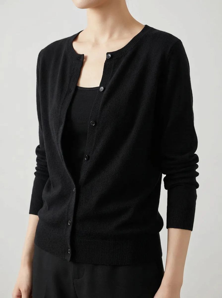 Close-up of a black knitted cardigan buttoned over a matching black top and trousers