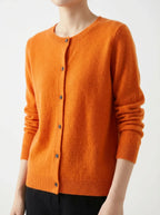 Side angle of a burnt orange knitted cardigan highlighting the soft knit texture and ribbed hem