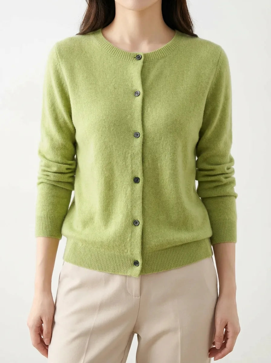 Front view of a lime green knitted cardigan with dark buttons, worn over beige trousers