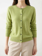 Front view of a lime green knitted cardigan with dark buttons, worn over beige trousers