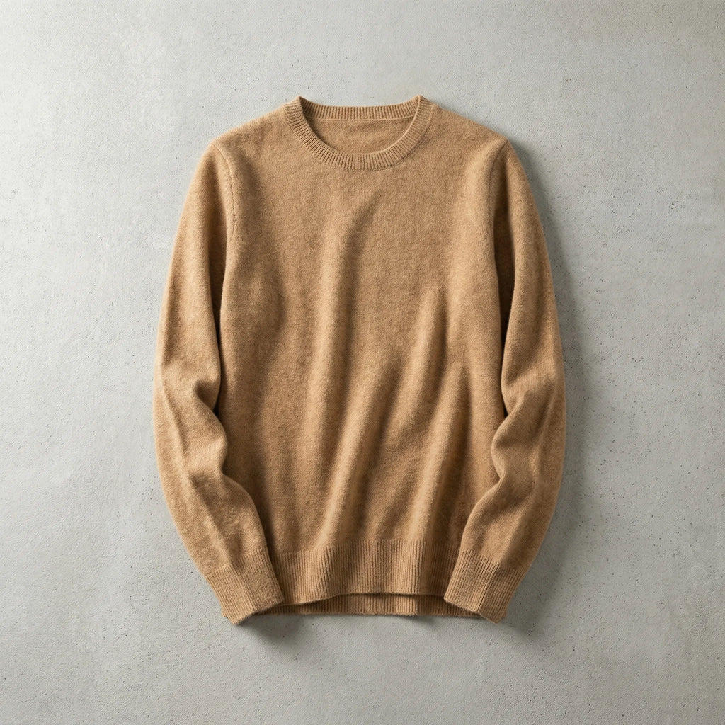 Folded camel brown merino wool jumper with ribbed crew neckline laid flat on a light grey surface