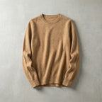 Folded camel brown merino wool jumper with ribbed crew neckline laid flat on a light grey surface