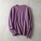 Folded mauve purple merino wool jumper with ribbed cuffs, laid flat on a soft grey surface