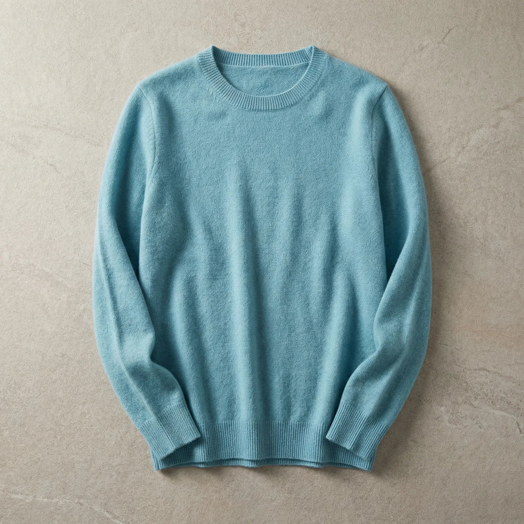 Folded pale blue merino wool jumper with ribbed hem and cuffs, laid flat on a warm beige backdrop