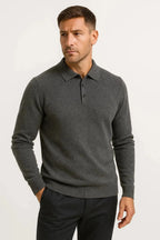 Man wearing a grey marl merino wool polo jumper with ribbed collar, three-button placket and dark trousers.