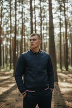 Man in navy bomber jacket looking off to the side, showcasing the smooth fabric finish and relaxed fit.
