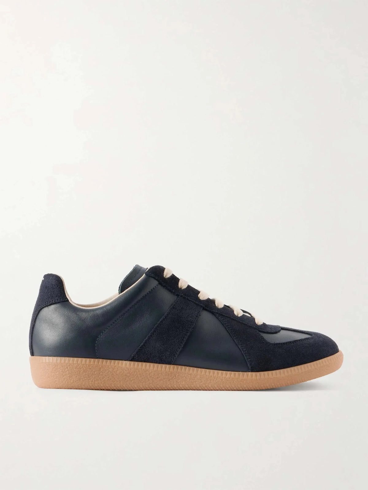 Side view of a navy leather and suede trainer with panelled upper, cream laces and a gum rubber sole