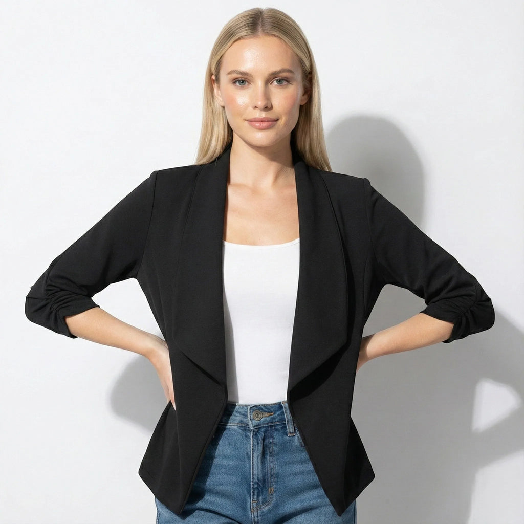 Woman wearing black open-front blazer over a white top, hands on hips, front view