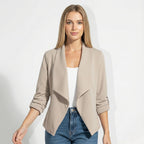 Woman wearing beige open-front blazer over a white top with jeans, front view close-up