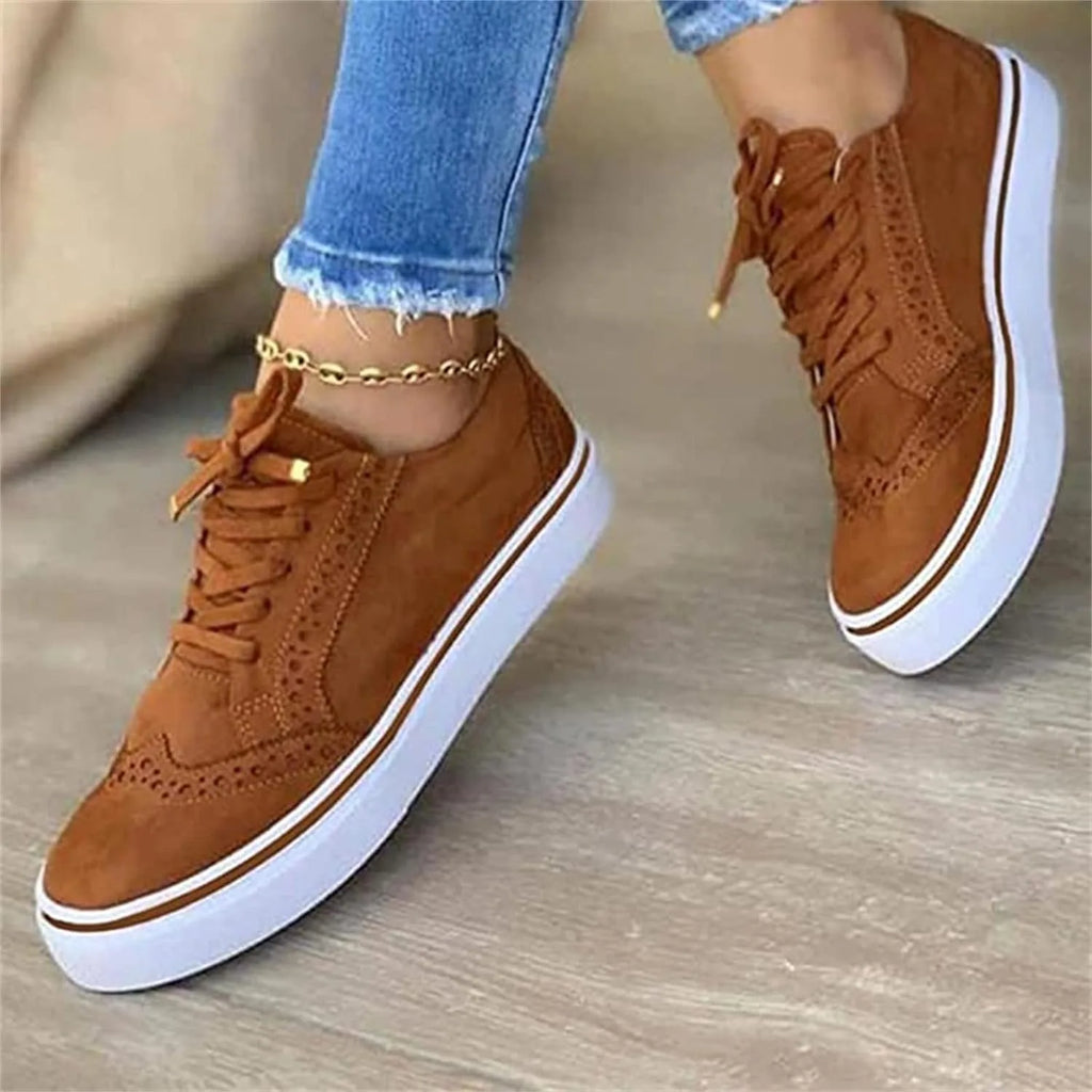 Close-up angled view of tan suede brogue trainers showing white platform sole and brown trim detail