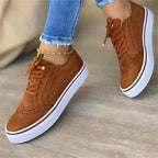Close-up angled view of tan suede brogue trainers showing white platform sole and brown trim detail
