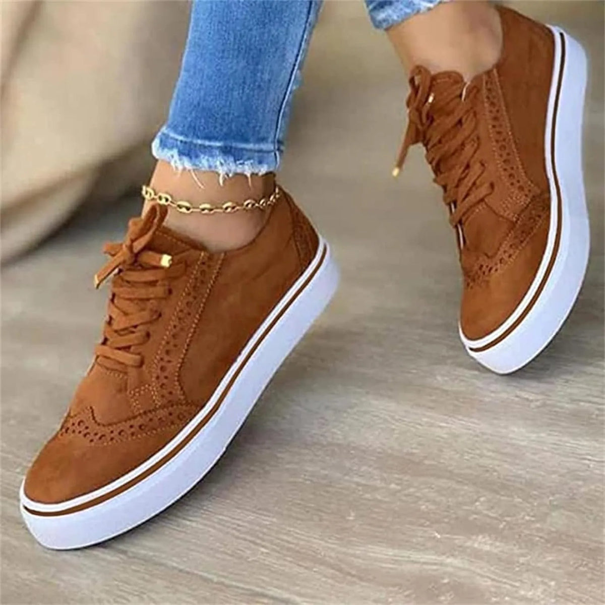 Close-up angled view of tan suede brogue trainers showing white platform sole and brown trim detail