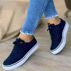 Navy blue suede lace-up trainers with brogue perforations and white platform sole, shown in motion