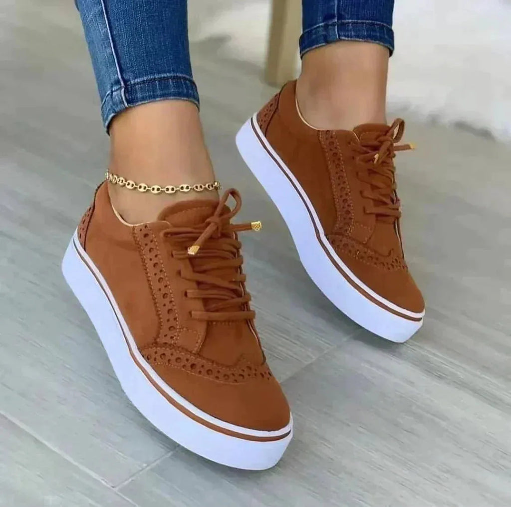 Close-up front view of tan suede brogue trainers highlighting lace detail and gold-tipped laces