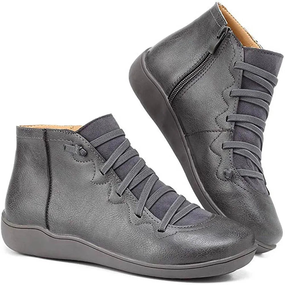 Grey ankle boots displayed in a pair, highlighting the low wedge sole and lace-up vamp