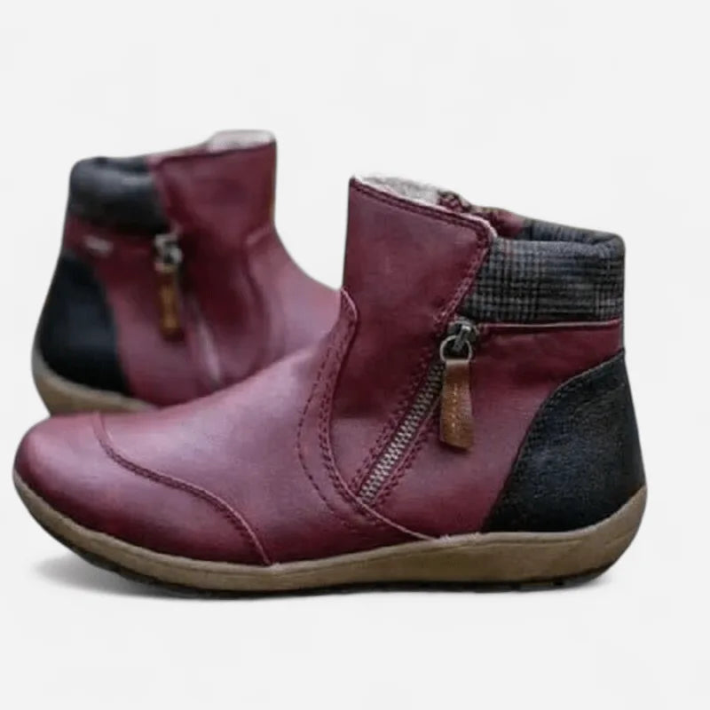 Burgundy leather ankle boots with side zip pull and thick tan outsole, side profile