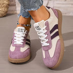 Pair of sage green trainers worn while seated, both shoes shown side by side
