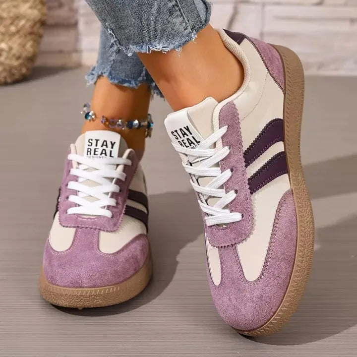 Pair of sage green trainers worn while seated, both shoes shown side by side