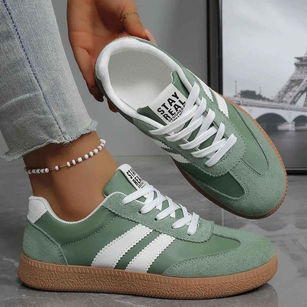 Navy blue canvas trainer with white stripes worn on foot, rear view showing heel tab