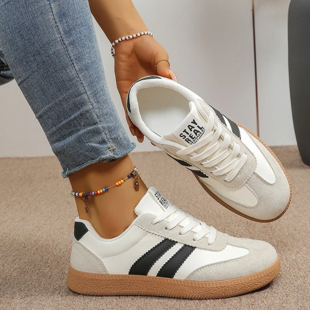 Front angled view of navy trainer with white laces and gum sole on model's foot
