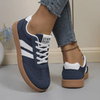 Sage green trainer held in hand showing padded ankle collar and lace-up front