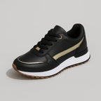 Studio shot of a single black trainer with metallic gold stripe, black laces and a white and gum two-tone sole