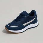Studio shot of a single navy trainer with a silver side stripe, navy laces and a white chunky sole on grey background