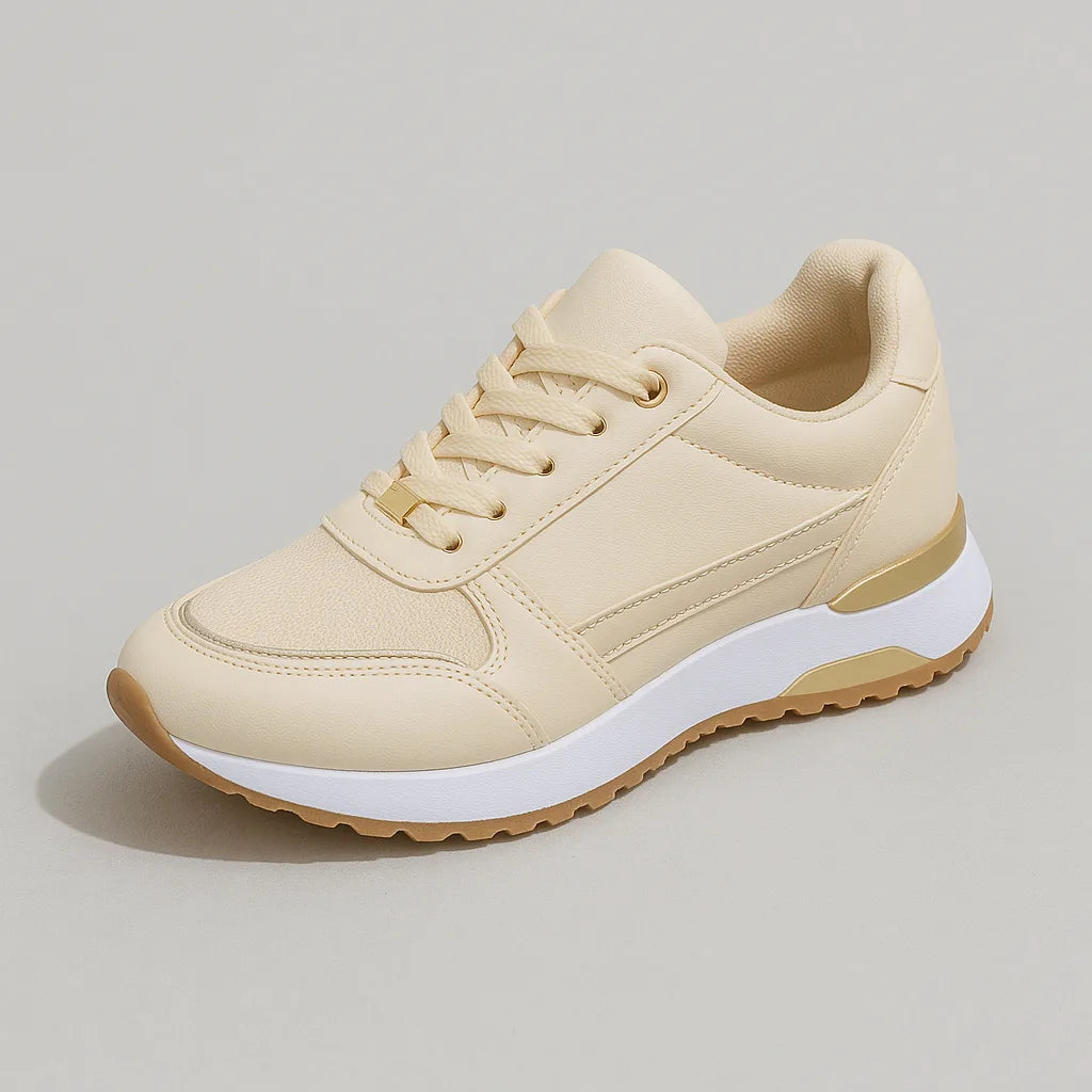 Studio shot of a single cream trainer with gold trim, matching laces and a white and gold chunky sole
