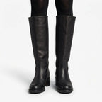 Front view of black pebbled leather knee high boots worn over black tights, showing full shaft height