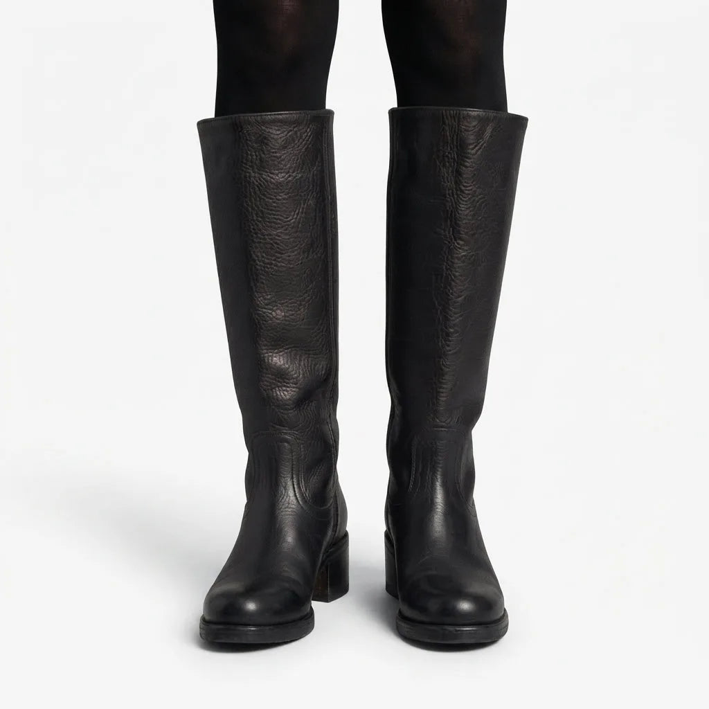 Front view of black pebbled leather knee high boots worn over black tights, showing full shaft height