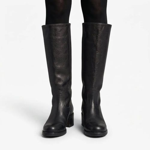 Front view of black pebbled leather knee high boots worn over black tights, showing full shaft height