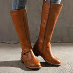 Tan brown knee-high boots shown from the front with visible zip and buckle strap accent