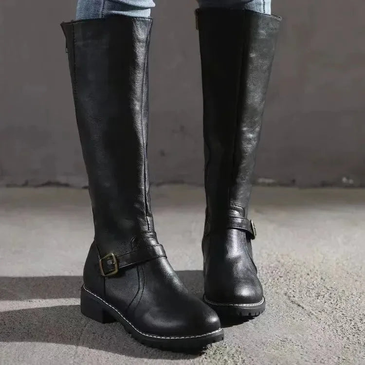 Close-up front view of black knee-high boots highlighting buckle hardware and rounded toe
