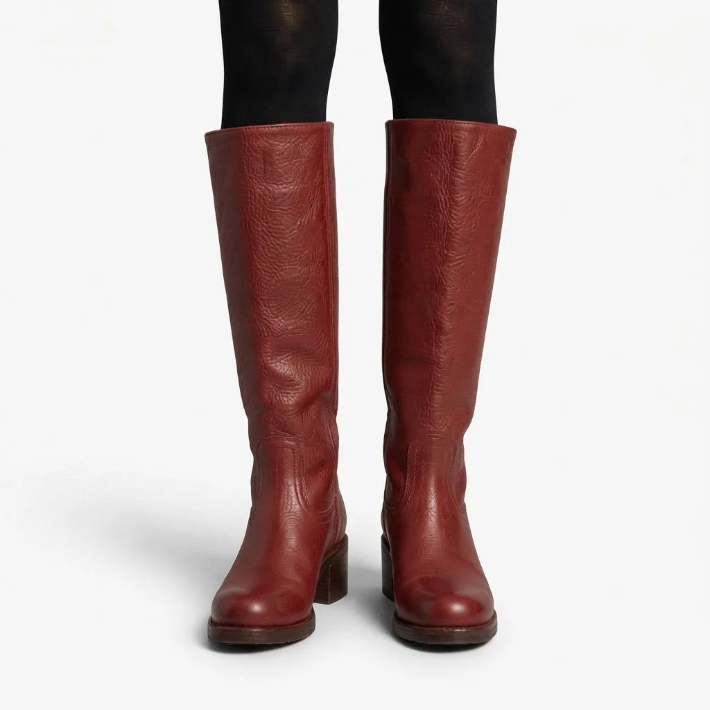 Front view of deep red leather knee high boots worn over black tights, showing smooth pebbled grain