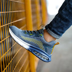 Close-up side profile of the blue mesh trainer's toe and air cushion sole against an orange wire mesh fence