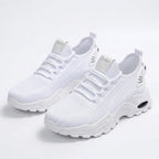 Pair of all-white knit trainers with chunky white tread sole viewed at an angle
