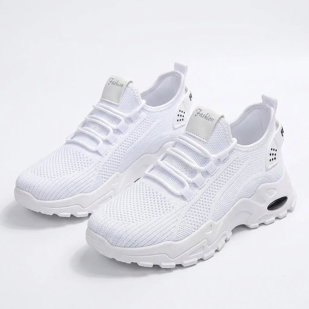 Pair of all-white knit trainers with chunky white tread sole viewed at an angle